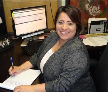 Female SERVPRO employee sitting at desk writing on paper