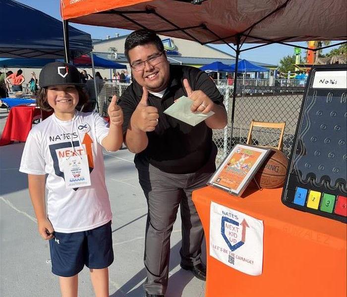 Male SERVPRO Employee standing next to child at an event 