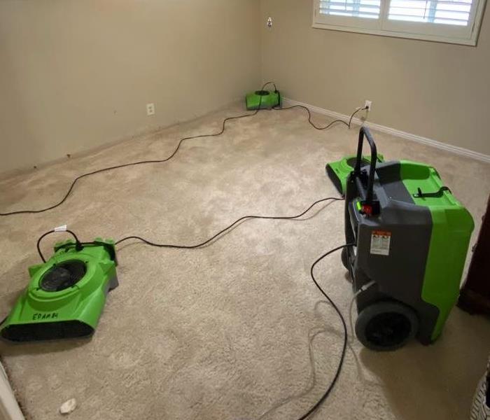 bedroom with flooring removed due to flood and SERVPRO equipment running